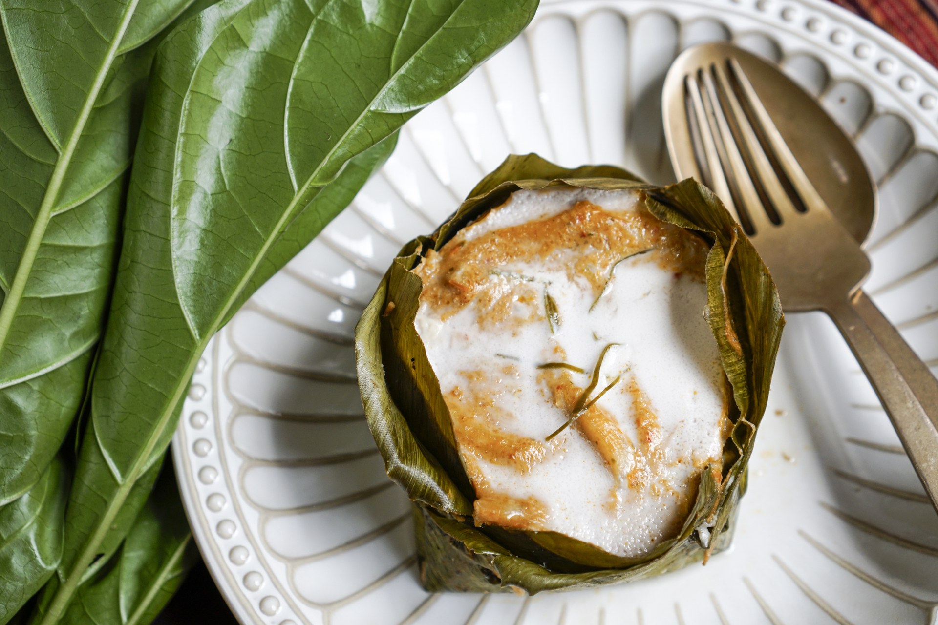 Kravanh’s fish amok, set in a banana-leaf cup with a coconut-cream top, beside a breadfruit leaf
