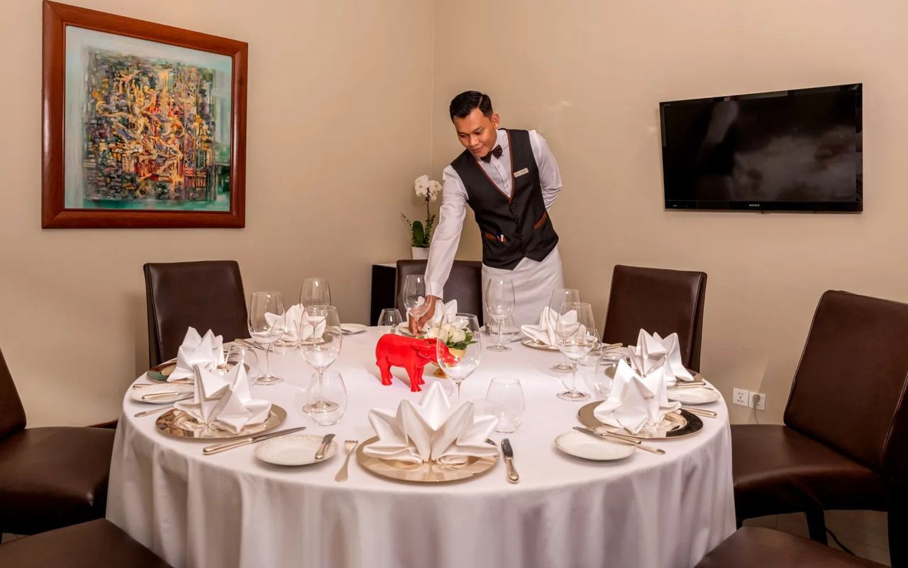 A private dining room at Topaz, a round table laid for dinner beneath a painting