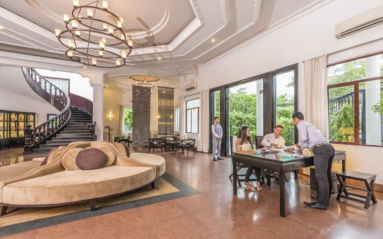 The lobby of White Mansion, with a curving staircase, chandelier and tall windows